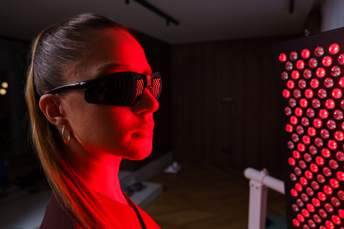 femeie utilizand panou cu lumina rosie pentru tratament acnee